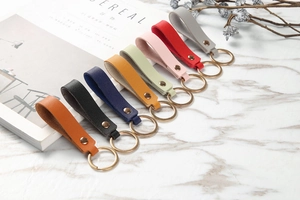 Flat lay of colorful leather keychains in eight colors on white marble surface