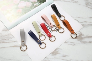 Flat lay of colorful PU leather keychains with gold metal rings on marble background