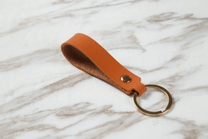 Macro view of brown lychee texture leather keychain with golden metal ring and rivet
