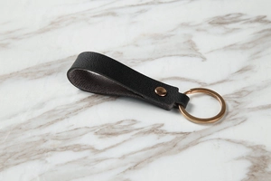 Detail of black lychee grain leather keychain with rose gold metal rivet and ring