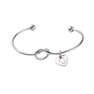 Silver stainless steel knot cuff bracelet with heart pendant featuring letter C engraving