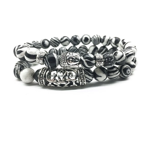Detailed macro of Buddha head charm on black and white striped agate bead bracelet