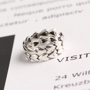 Vintage S925 sterling silver ring with interlocking heart design on a printed background
