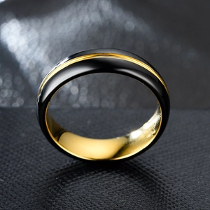 Polished two-tone black and gold stainless steel ring for men and women on dark background