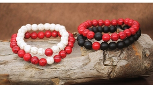 Detail of red, white marble, and matte black 8mm stone beads on a natural wood stand