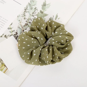 Detailed texture of dark green polka dot fabric scrunchie on an aesthetic book background