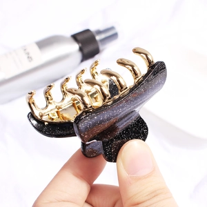 Elegant black acrylic claw clip with gold glitter finish and metal spring