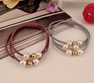 Detail of grey and purple triple-strand elastic hair ties with pearls and gold beads