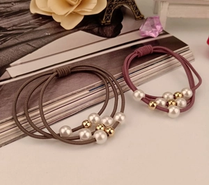 Detailed view of handmade three-strand elastic hair ties with pearls in brown and pink