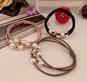Three elastic hair ties with white imitation pearls and gold beads in soft colors