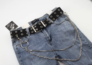 Detail of blue denim jeans with black double-eyelet canvas belt and silver metal chains