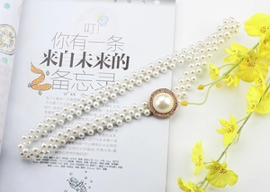 Detail of elastic pearl belt featuring a rhinestone buckle on a vintage dress accessory