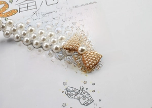 Close-up of elegant pearl waist belt featuring a detailed beaded bow and rhinestone