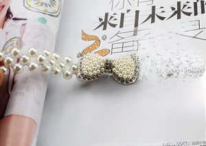 Elegant pearl elastic waist belt with rhinestone bow buckle on a lifestyle magazine