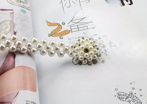 Close-up of elastic pearl belt with a crystal-studded square buckle on a magazine background