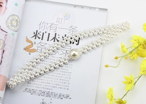 Detail of multi-row pearl waist chain with rhinestone buckle on a fashion magazine