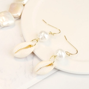 Detail of bohemian gold hook earrings with white pearl and natural seashell drop