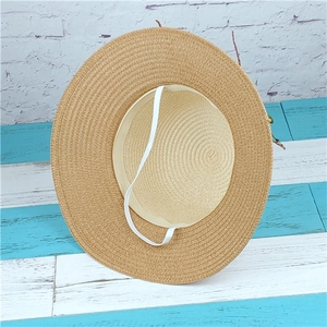 Two-tone woven straw sun hat with wide brim and white chin strap on wooden surface