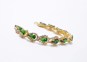 Détail du bracelet doré avec pierres en forme de goutte émeraude et cristaux brillants