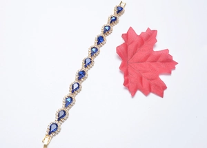 Gros plan du bracelet doré orné de cristaux bleus en forme de goutte et de strass étincelants