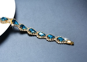 Vue détaillée d'un bracelet doré avec cristaux bleus en forme de goutte et petits diamants
