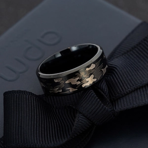 Polished black titanium camo pattern ring displayed on a premium gift box background