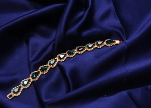 Détail d'un bracelet en cristal poire bleu foncé sur fond de satin bleu
