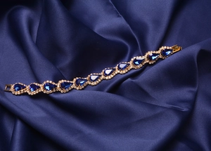 Bracelet doré avec cristal goutte bleu et strass brillants sur satin bleu doux