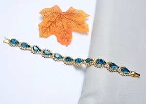 Détail d'un bracelet en or avec cristaux goutte d'eau bleus et petits diamants brillants