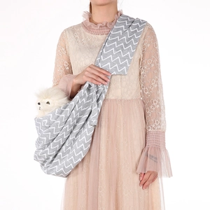 Gray pet carrier sling with white wave pattern shown on model in studio setting