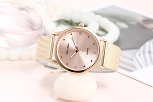 Détail d'une montre à quartz rose doré avec bracelet en maille et cadran diamanté