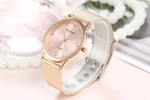 Détail de la montre à quartz or rose avec index en cristal et bracelet en maille
