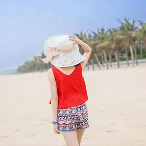 Detailansicht eines Kinder-Strandoutfits mit Strohhut, Schleife und roter Sommerweste