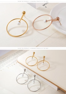 Macro detail of geometric pearl earrings in gold and silver finish on white porcelain