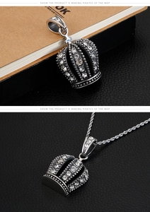 Detail of hip hop crown pendant with pavé set crystals on a polished steel chain
