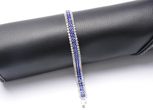 Detail of silver plated bracelet with blue and white crystals on black display stand