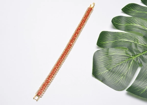 Detailed view of a gold-plated multi-row bracelet with red and clear zircon stones