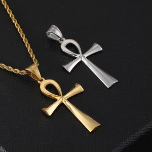 Polished gold and silver Egyptian Ankh cross pendants on a black textured surface