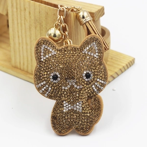 Detailed close-up of brown cartoon cat pendant with rhinestones, golden bell and tassel