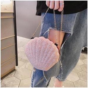 Detailed view of pink sequin shell-shaped crossbody bag with gold chain and pearl charm
