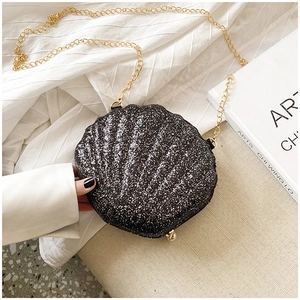 Detail of black glitter shell crossbody bag with elegant gold chain on a minimalist background