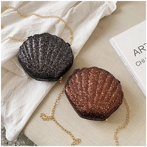 Detailed view of glittering shell-shaped mini bags in black and brown with gold chains