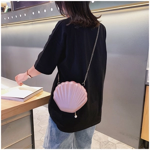 Pink shell-shaped crossbody bag with pearl charm detail and gold metal chain strap