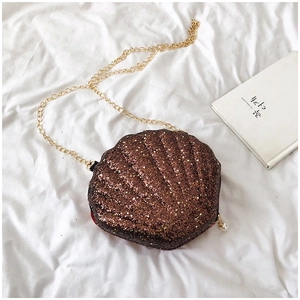 Detailed macro of brown glitter shell-shaped crossbody bag with golden chain and pearl charm