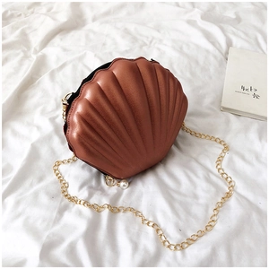 Close-up of metallic bronze shell bag with gold chain and pearl zipper detail