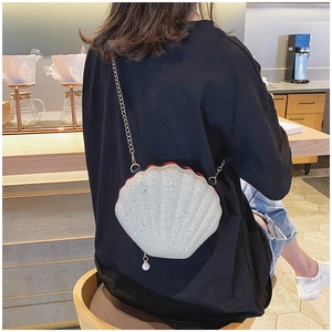 Detail of white sequin shell-shaped bag with pearl charm and gold chain strap