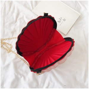 Detail view of pink shell bag with red lining, gold chain and zipper closure
