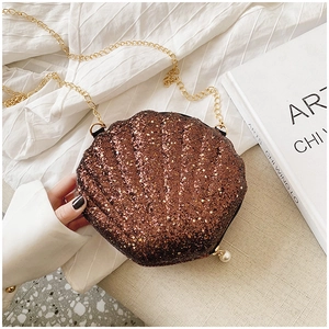 Brown sequin shell bag with gold chain strap and pearl clasp detail on white fabric