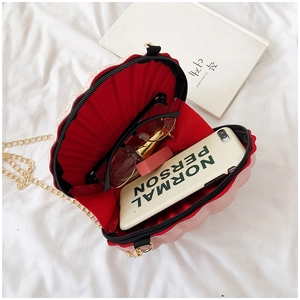 Detail view of pink shell bag interior with phone and lipstick in red lining