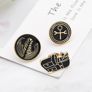 Gros plan de trois broches en émail noir et or sur le thème du café en métal détaillé